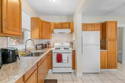 a kitchen with wooden cabinets and a white refrigerator at UNH Home Base 10 minutes from beach in West Haven