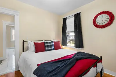 a bedroom with a bed with red pillows and a clock at UNH Home Base 10 minutes from beach in West Haven