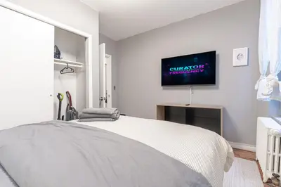 a white bedroom with a bed and a tv on the wall at Chic 3Bd 1Bth Near Empire State in New York