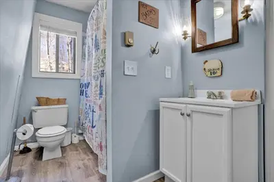 a bathroom with a toilet and a sink and a mirror at Pet Friendly! Lakefront w Hot Tub, Firepit! in Tobyhanna