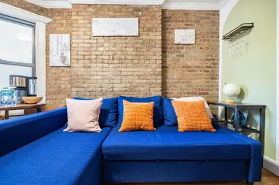 a blue couch in a room with a brick wall at 2 Bedroom Home Unit In Lower Manhattan in New York
