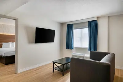 a room with a bed and a chair and a television at Baldwin Inn & Suites, SureStay Collection by Best Western in West Springfield