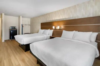 two beds in a hotel room with white sheets at Baldwin Inn & Suites, SureStay Collection by Best Western in West Springfield
