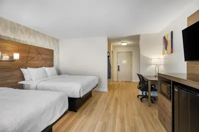 a hotel room with two beds and a desk at Baldwin Inn & Suites, SureStay Collection by Best Western in West Springfield