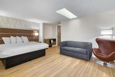 a hotel room with a bed and a chair at Baldwin Inn & Suites, SureStay Collection by Best Western in West Springfield