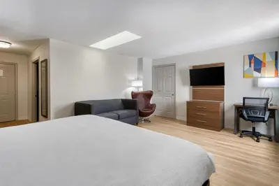 a hotel room with a bed and a desk and a television at Baldwin Inn & Suites, SureStay Collection by Best Western in West Springfield