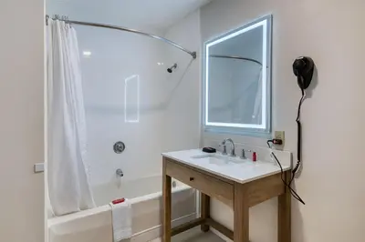 a white bathroom with a sink and a shower at Baldwin Inn & Suites, SureStay Collection by Best Western in West Springfield