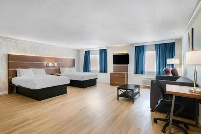 a hotel room with two beds and a desk at Baldwin Inn & Suites, SureStay Collection by Best Western in West Springfield