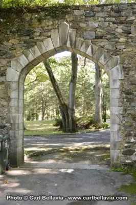 an archway in a stone wall in a park at Midcentury Modern ZenHouse Sculptor Studio in Stamford