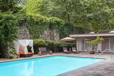 a swimming pool with two chairs and an umbrella at Midcentury Modern ZenHouse Sculptor Studio in Stamford