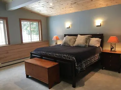 a bedroom with a large bed and two windows at Stratton Chalet in Stratton