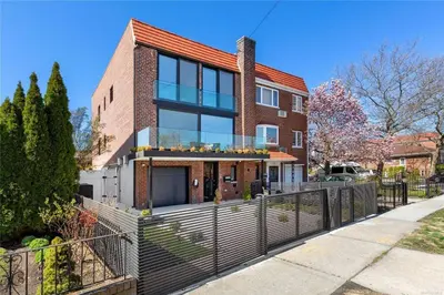 a brick house with a fence in front of it at 2 Story Villa in Upper Ditmars Astoria Queens in Steinway