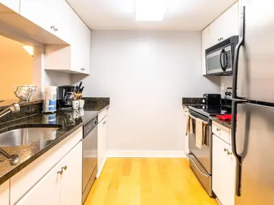 a kitchen with white cabinets and a stainless steel refrigerator at Centrally Located Apt Downtown in Stamford