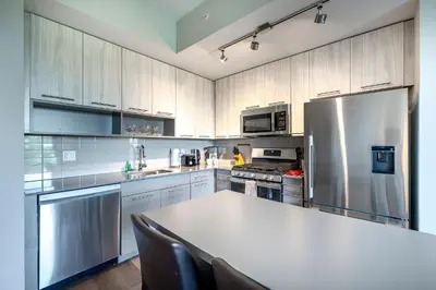 a kitchen with a table and a stainless steel refrigerator at Modern Apt with Luxury Amenities in Stamford