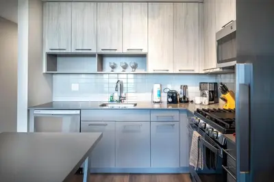 a kitchen with white cabinets and a sink and a stove at Modern Apt with Luxury Amenities in Stamford