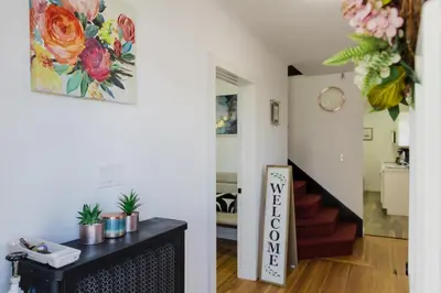 a room with a staircase and a living room with flowers on the wall at Harty's Terrace 9 Kimball Avenue in Yonkers