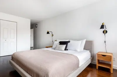 a bedroom with a large white bed with two lamps at Blueground Chelsea gym doorman nr market NYC-494 in New York