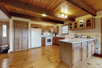 a kitchen with wooden cabinets and a white refrigerator at Green Mountain Sunrise in Dover