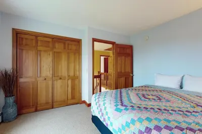 a bedroom with a bed and a wooden closet at Green Mountain Sunrise in Dover