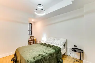 a bedroom with a bed and a table and chairs at Walk to Journal Square Modern Apt about 4 Mi to NYC! in Jersey City