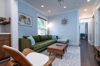 a living room with a green couch and a table at Fully-stocked Kitchen, AC, WiFi, WD, Near Baseball and Downtown in Oneonta