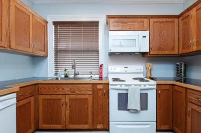 a kitchen with wooden cabinets and a white stove top oven at Fully-stocked Kitchen, AC, WiFi, WD, Near Baseball and Downtown in Oneonta