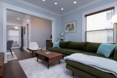 a living room with a green couch and a table at Fully-stocked Kitchen, AC, WiFi, WD, Near Baseball and Downtown in Oneonta