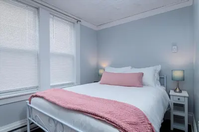 a bedroom with a bed with a pink blanket on it at Fully-stocked Kitchen, AC, WiFi, WD, Near Baseball and Downtown in Oneonta
