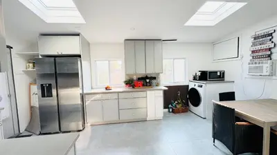 a kitchen with white cabinets and a stainless steel refrigerator at Fancy private home
