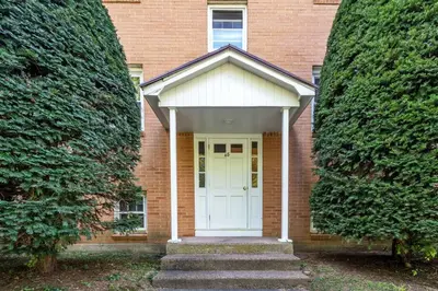 a white front door of a brick house with stairs at Crested One Place in Manchester