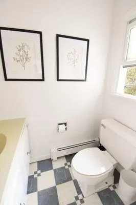 a bathroom with a toilet and two pictures on the wall at Hudson Valley Haven - NY in Red Hook