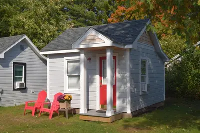 a small house with two red chairs in the yard at Saratoga Cabins in Malta