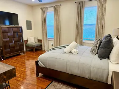 a bedroom with a large bed and two windows at Saugerties Waterfront Getaway in Saugerties