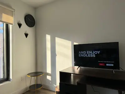 a living room with a flat screen tv on a dresser at Cozy apt with City skyline rooftop in Union City