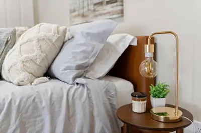 a bed with white pillows and a lamp on a table at Hip Dtwn Apt With Arcade And Gym in Binghamton