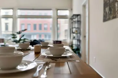 a wooden table with cups and saucers on it at Hip Dtwn Apt With Arcade And Gym in Binghamton