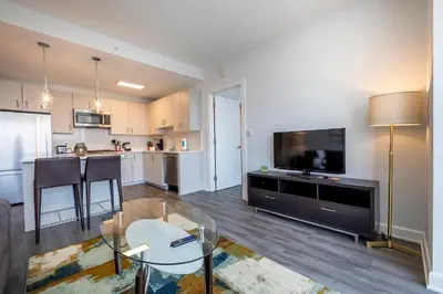 a living room with a table and a kitchen with a tv at Luxury Apt Near Downtown in Stamford