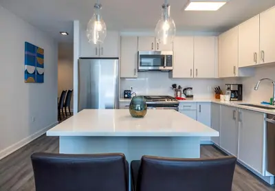 a kitchen with white cabinets and a large island with chairs at Luxury Apt Near Downtown in Stamford