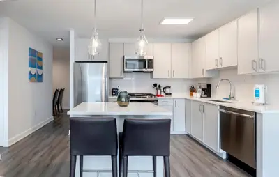 a kitchen with white cabinets and a kitchen island with black chairs at Luxury Apt Near Downtown in Stamford