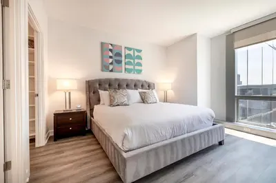 a white bedroom with a large bed and a window at Luxury Apt Near Downtown in Stamford