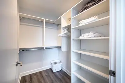 a walk in closet with white shelves and wood floors at Luxury Apt Near Downtown in Stamford