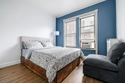 a bedroom with blue walls and a bed and a chair at Ultimate Urban living at Centrally Located Apartments in New York