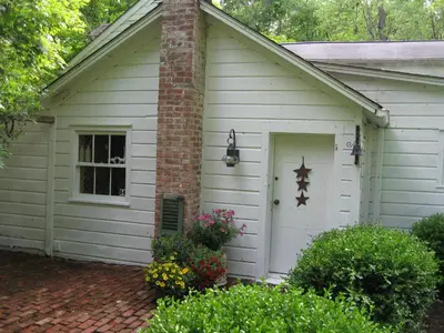 a small white house with a door and flowers at Omega Special, Sun thru thurs 5 night minimum in Clinton Corners