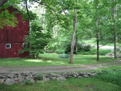 a path next to a red barn and trees at Omega Special, Sun thru thurs 5 night minimum in Clinton Corners
