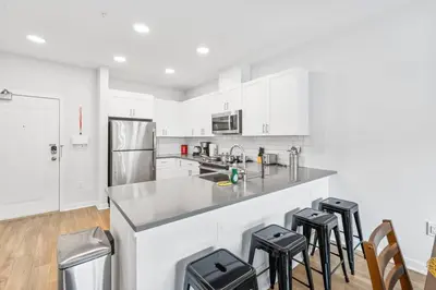 a kitchen with white cabinets and a counter with stools at Luxury Living in Jersey City Only Steps Away from Manhattan in Jersey City