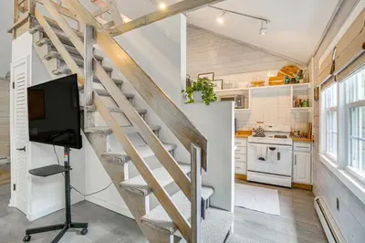 a kitchen with a spiral staircase and a tv in a room at Serene Holmes Cottage Near Lakes and Trails! in Pawling