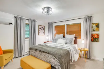a bedroom with a large bed and a yellow chair at Serene Holmes Cottage Near Lakes and Trails! in Pawling