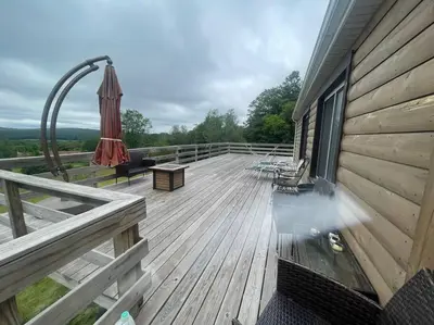 a wooden deck with an umbrella and chairs on a house at Most relaxing place on earth in Livingston Manor