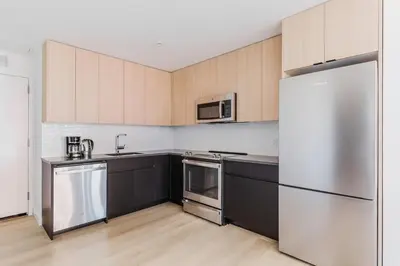 a kitchen with stainless steel appliances and wooden cabinets at Blueground Jersey City gym wd ac games NYC-1580 in New York