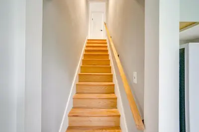 a staircase in a house with white walls and wooden floors at 2 Mi to Windham Mountain Scenic Home with Fire Pit! in Windham